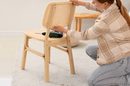 Young woman assembling chair at homeの写真素材