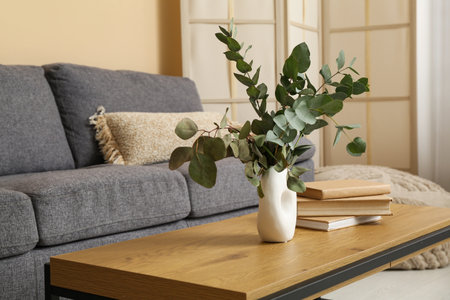 Books and vase with eucalyptus branches on table in interior of living roomの写真素材