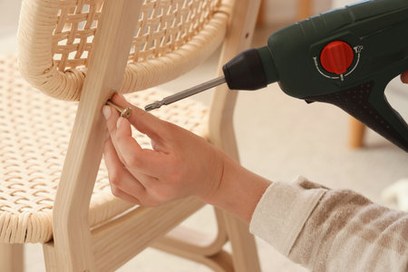 Female hands with drill assembling chair at home, closeup