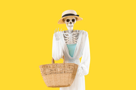 Human skeleton with summer clothes and beach bag on yellow backgroundの写真素材