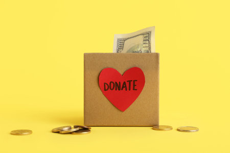 Box with money on yellow background. Donation concept