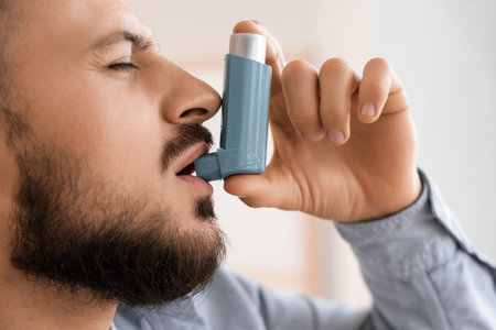 Young man using inhaler at home, closeupの写真素材