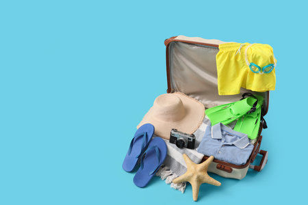 Suitcase with clothes and beach accessories on blue backgroundの写真素材