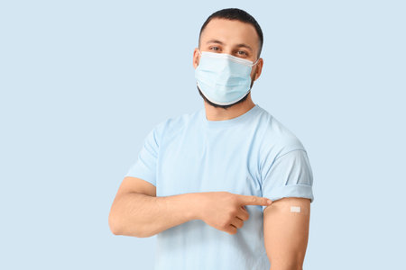 Young man with applied medical patch on blue background. Immunization concept