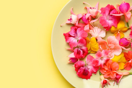 Plate with different beautiful edible flowers on yellow backgroundの写真素材