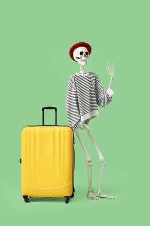 Human skeleton in beret with suitcase on green background. Travel conceptの写真素材
