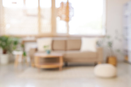 Blurred view of living room with gray sofa, table and windowの写真素材