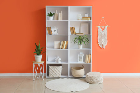 Bookshelf with decor and plants near color wall in room
