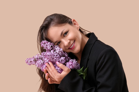 Beautiful young woman with blooming lilac flowers on brown backgroundの写真素材