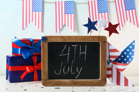 Chalkboard with text 4TH JULY, USA flags and gift boxes on table against white grunge background. Independence Day celebrationの写真素材