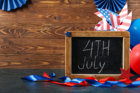 Chalkboard with text 4TH JULY and ribbons on table against wooden background. Independence Day celebrationの写真素材