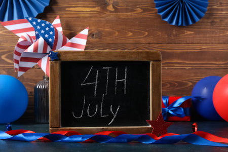 Chalkboard with text 4TH JULY and ribbons on table against wooden background. Independence Day celebrationの写真素材