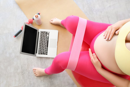 Sporty pregnant woman with stretching band at home, top viewの写真素材
