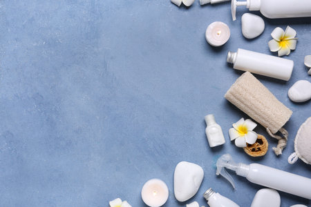 Beautiful composition with different spa supplies and plumeria flowers on blue backgroundの写真素材