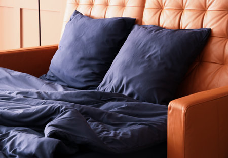 Leather bed with stylish blue bedding near brown wall in bedroom