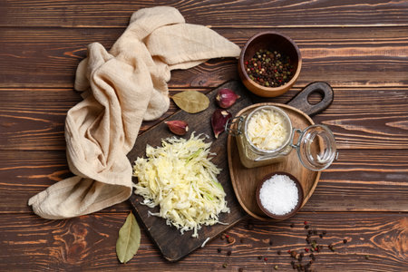 Jar with tasty sauerkraut and different ingredients on wooden backgroundの写真素材