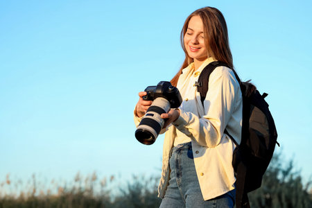 Young female photographer with camera in park at sunset