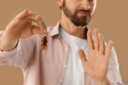 Young man with bug on beige background, closeup