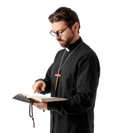 Handsome priest in eyeglasses reading Holy Bible on white background