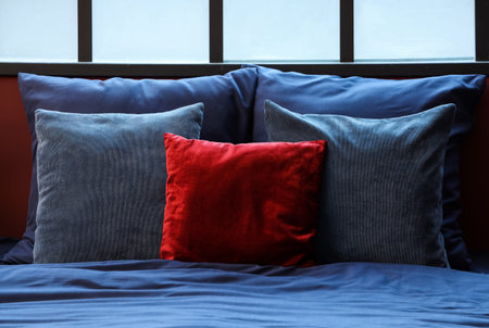 Bed with navy blue linen and red pillow in room