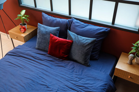 Bed with navy blue linen and red pillow in room