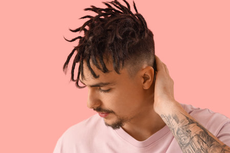 Young man with dreadlocks on pink background, closeup
