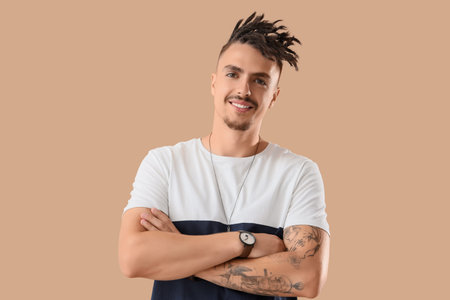 Young man with dreadlocks on beige background