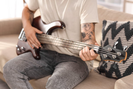 Young man playing guitar on sofa at home