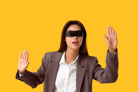 Beautiful young businesswoman in modern black VR glasses on yellow backgroundの写真素材