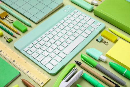 Computer keyboard and different school supplies on green background, closeupの写真素材