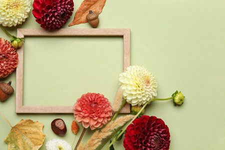 Composition with frame, beautiful dahlia flowers and dried leaves on green backgroundの写真素材