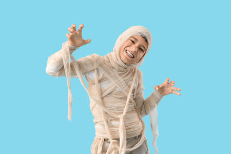 Little boy dressed as mummy for Halloween on blue backgroundの写真素材