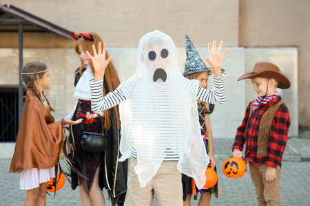 Little boy dressed as ghost for Halloween with his friends outdoorsの写真素材