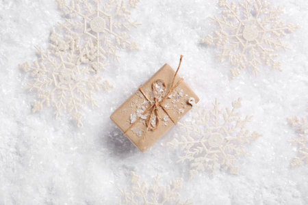 Composition with decorative snowflakes and gift box on snow as background, closeupの写真素材