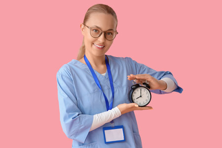 Female doctor with alarm clock on pink background. Time management concept
