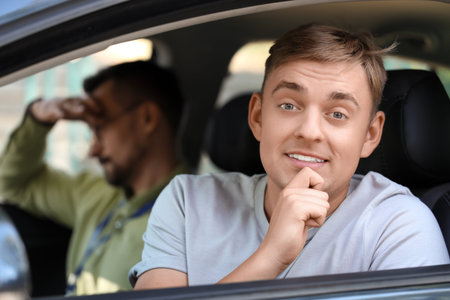 Young man failing driving license test with instructor outdoors, closeup