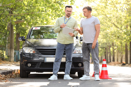 Upset young man passing driving license test with instructor on streetの写真素材