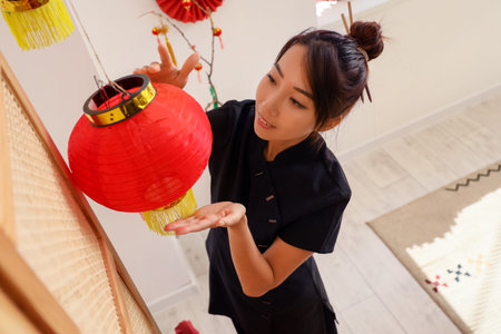 Young Asian woman hanging lantern in traditional Chinese roomの写真素材