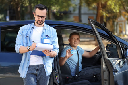 Male instructor with examiner after passing driving license test outdoors