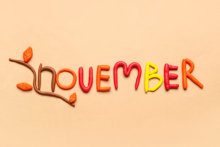 Word NOVEMBER made of play dough on beige background