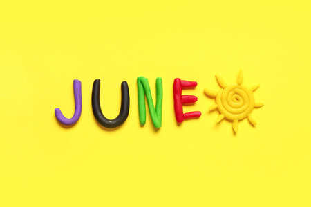 Word JUNE made of play dough on yellow background