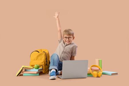Little boy with laptop and books studying computer sciences on beige background