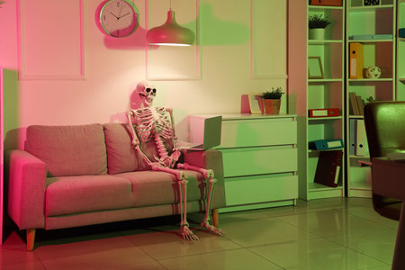 Skeleton model with laptop on sofa in office