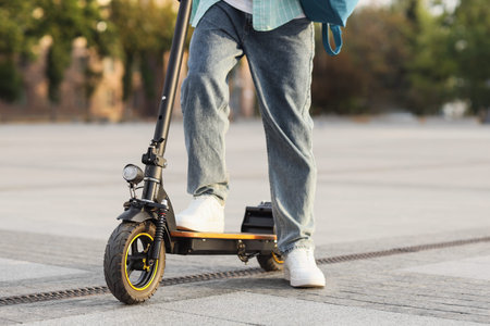 Young man riding electric scooter on city street, closeup