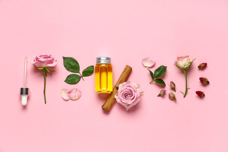 Composition with bottle of rose and cinnamon essential oil on pink background