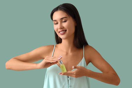 Beautiful woman holding serum with vitamin E on green background