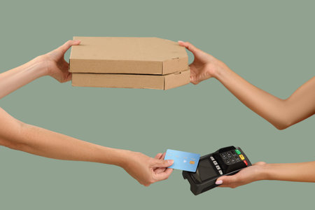 Hands with pizza boxes and payment terminal on green background