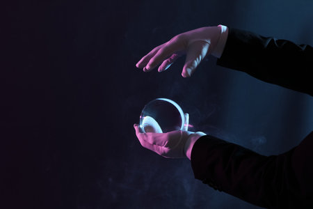 Male magician's hands with crystal ball and smoke on dark backgroundの写真素材