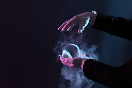 Male magician's hands with crystal ball and smoke on dark backgroundの写真素材