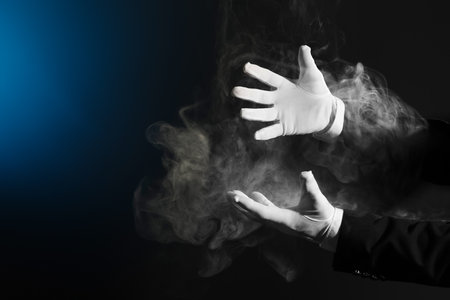 Male magician's hands with smoke on dark backgroundの写真素材